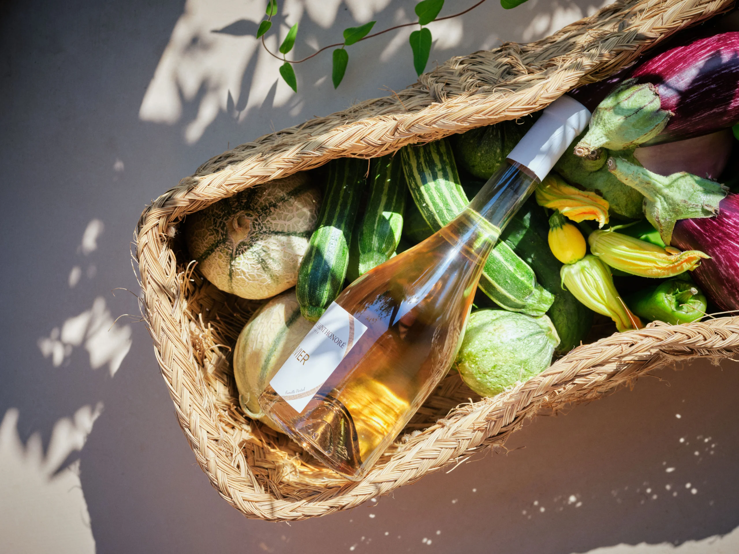 Un panier rempli de légumes frais et d'une bouteille de vin rosé.