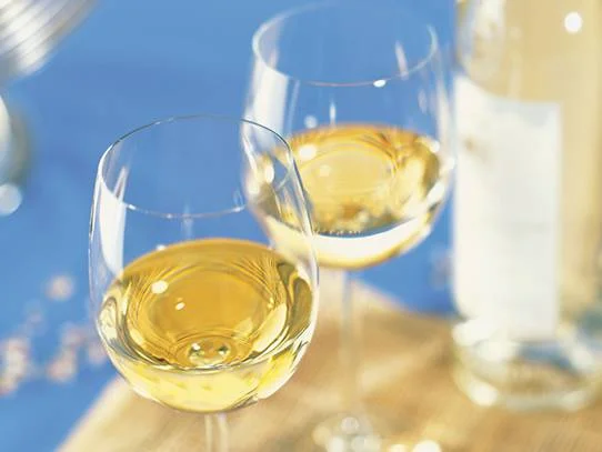 Deux verres de vin blanc doré sur une table bleue, un moment de détente.