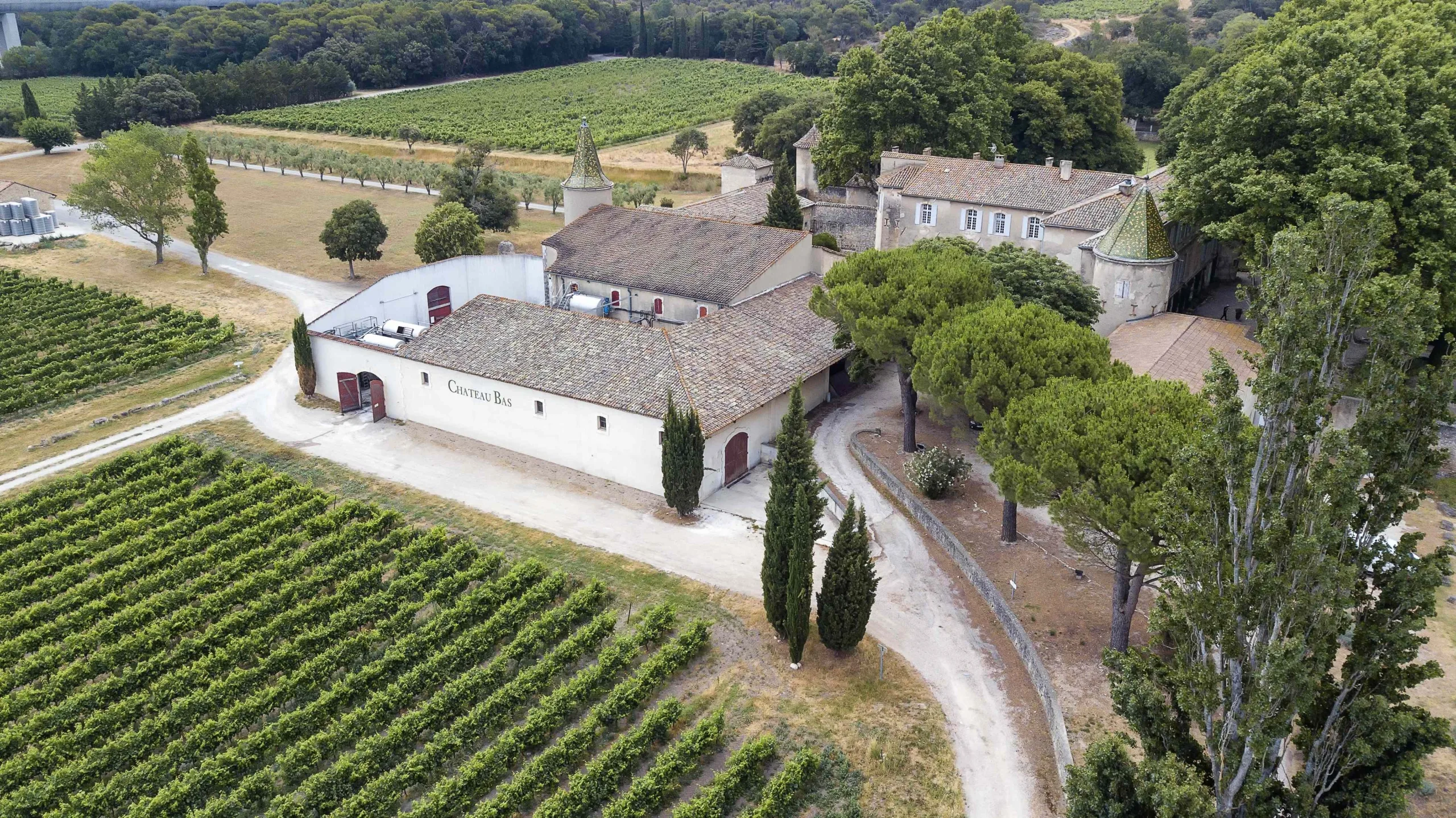 Vue aérienne du Château Bass, entouré de vignes dans le paysage français.