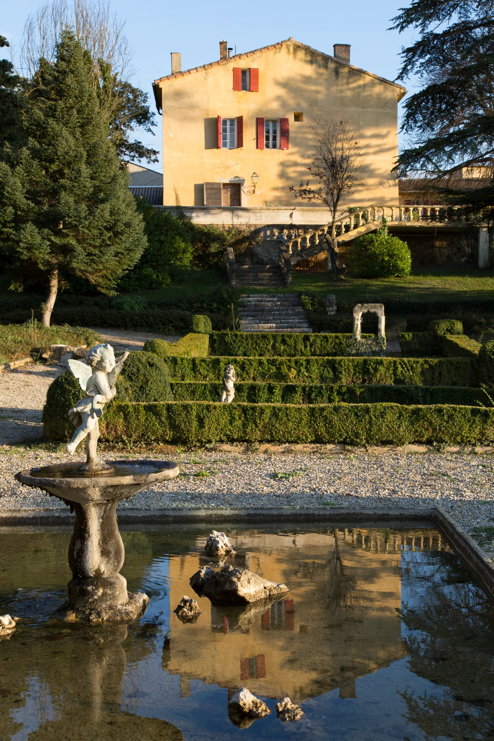 Belle demeure avec jardin paysagé et fontaine, reflet d'un paysage idyllique.